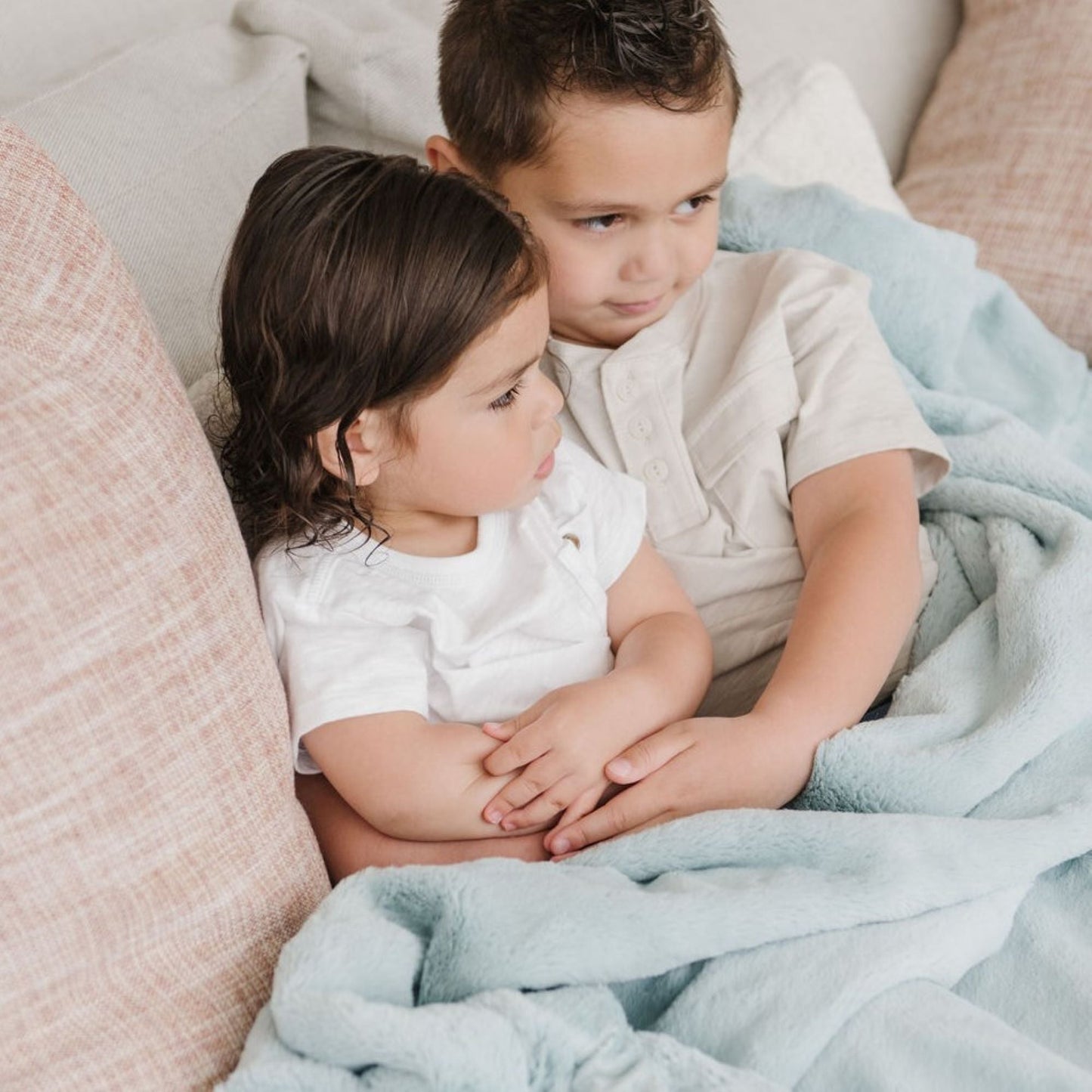 A little boy and a little girl sit under a Luxury Receiving Dew (light blue) Colored Lush Saranoni Blanket. The soft blanket is a small blanket and a baby blanket or toddler blanket.
