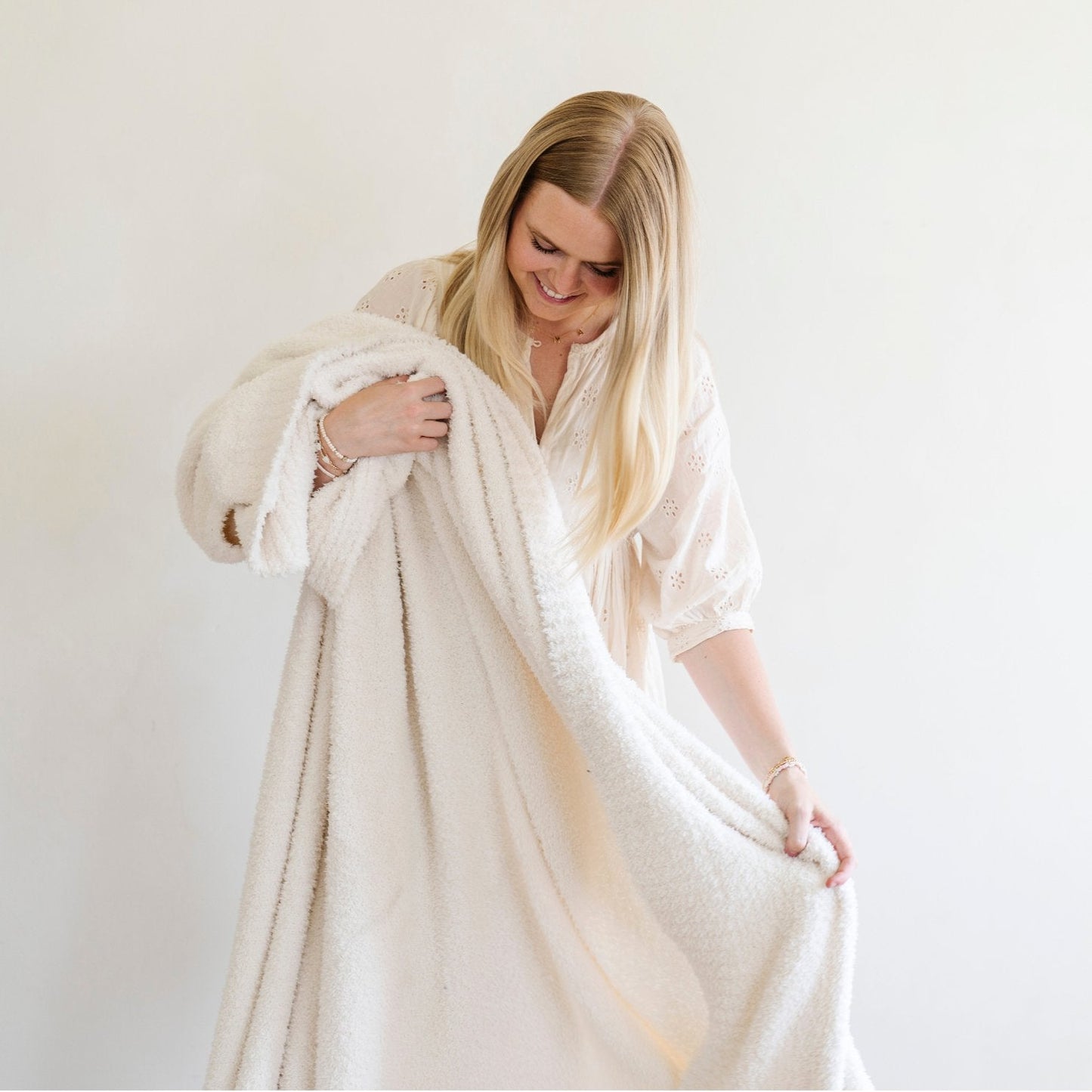 A woman holds an ivory bamboni® blanket. The soft blanket is a Saranoni blanket and a luxury blanket.