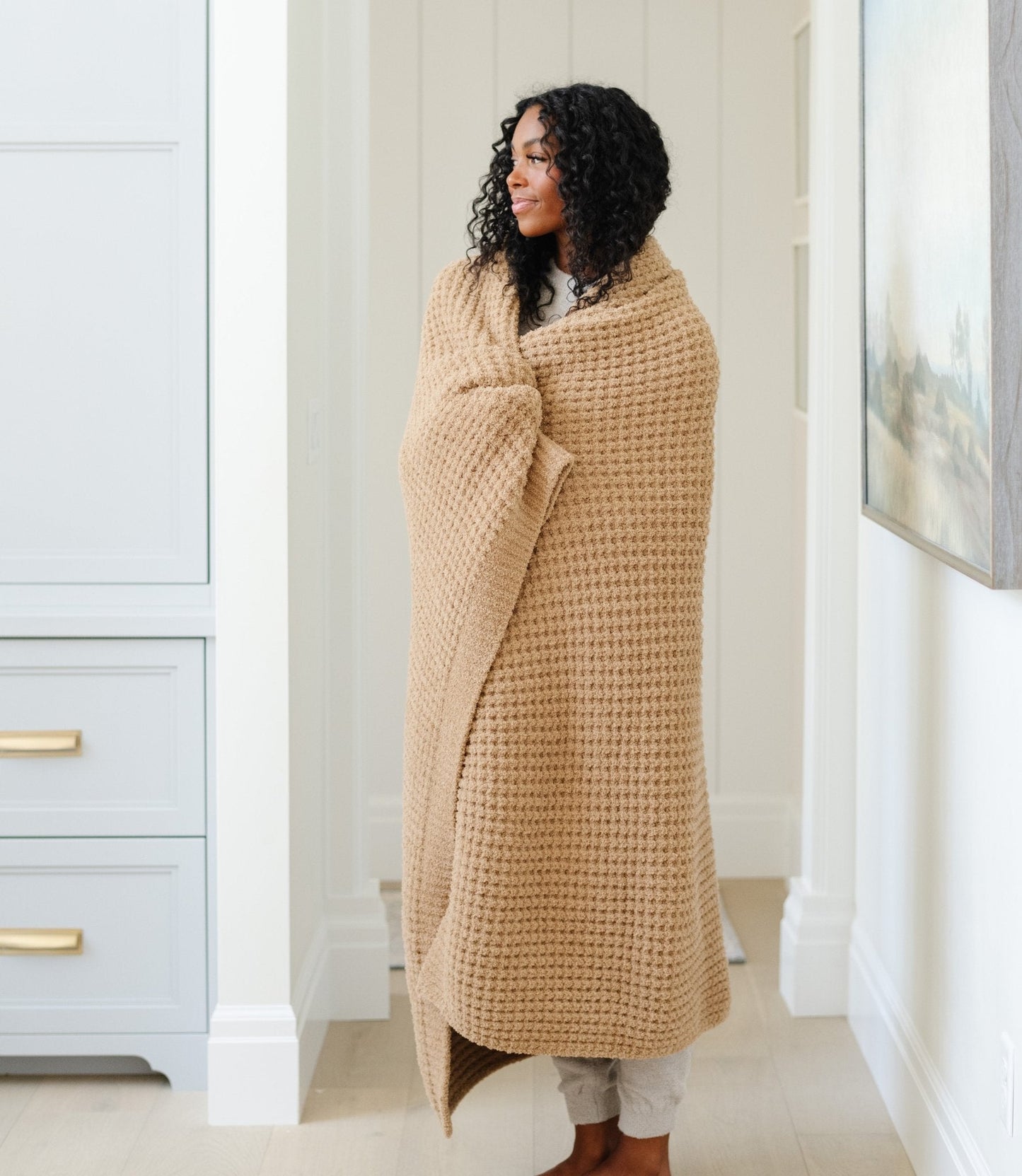 Woman wrapped up in a cozy, tan XL waffle knit blanket.