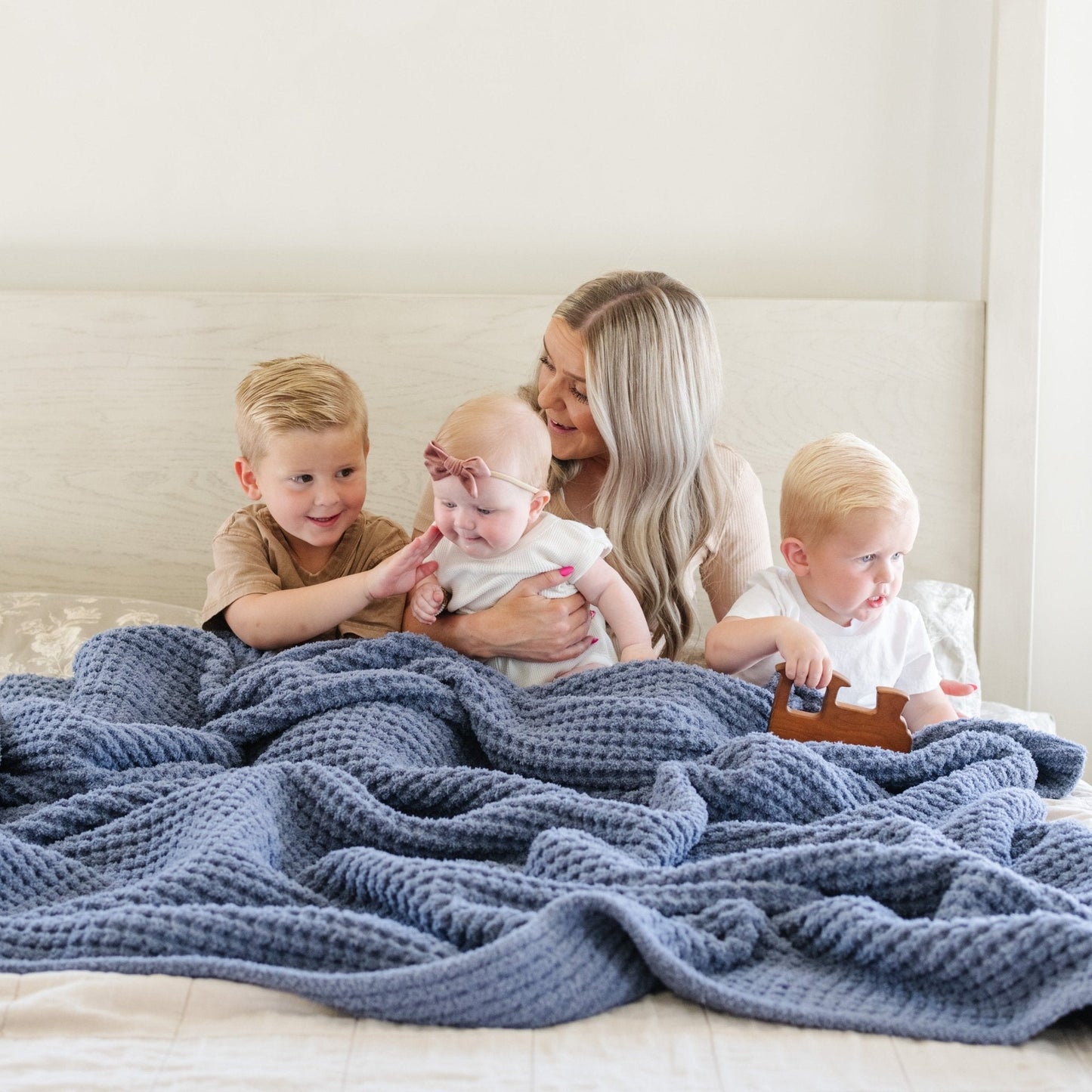 Mom and kids laying with blue waffle knit blanket.