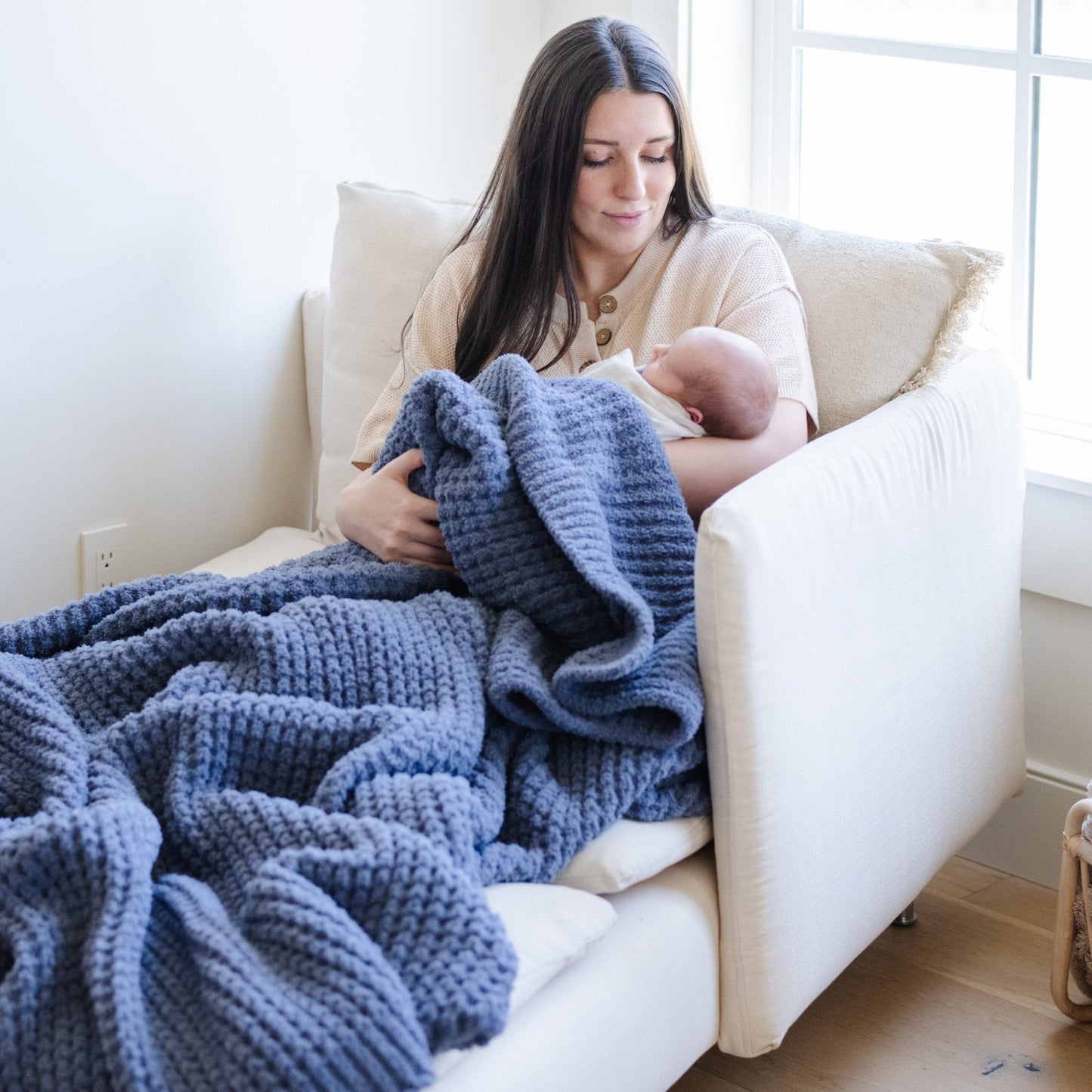 Mom and baby wrapped in blue waffle knit blanket.
