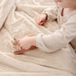 A little girl plays on Luxury Receiving Buttermilk (light tan) Colored Lush Saranoni Blanket. The soft blanket is a small blanket and a baby blanket or toddler blanket.
