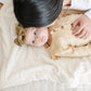 A baby girl lays on a Luxury Receiving Natural (off-white) Colored Lush Saranoni Blanket. The soft blanket is a small blanket and a baby blanket or toddler blanket.