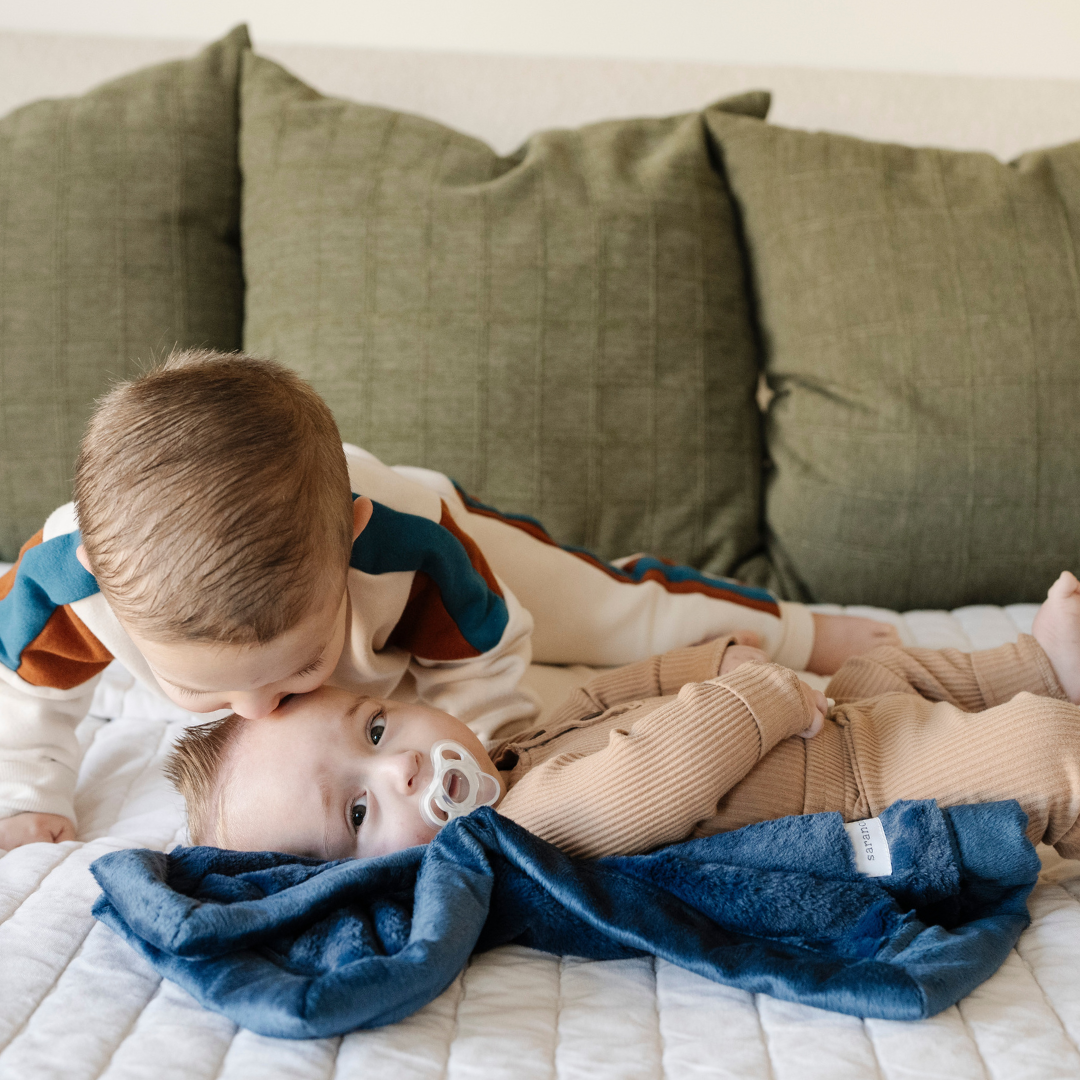 Two little boys and a mini blanket that is a navy blanket. The soft blanket is a lush blanket and a baby blanket as well as a Saranoni blanket. This cozy blanket is a luxury blanket for babies and is so soft.