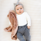 A baby girl and a mini blanket that is a dusty peach colored blanket. The soft blanket is a lush blanket and a baby blanket as well as a Saranoni blanket. This cozy blanket is a luxury blanket for babies and is so soft.