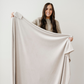 A woman holds a light neutral minky stretch blanket. This throw blanket is a Saranoni blanket and has a very soft texture. This blanket is perfect for gifting, lounging, or when you are on the go. 