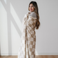 A woman is wrapped in a tan and cream checkered minky stretch blanket. This soft blanket is a Saranoni luxury blanket, and it is very stretchy, durable, and breathable. This extra large throw blanket is a very cozy blanket as well. 