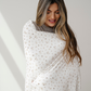 A woman is wrapped in a floral patterned minky stretch throw blanket. This Saranoni blanket is perfect for gifting, lounging, and taking on the go. This soft blanket is also very stretchy and durable. 