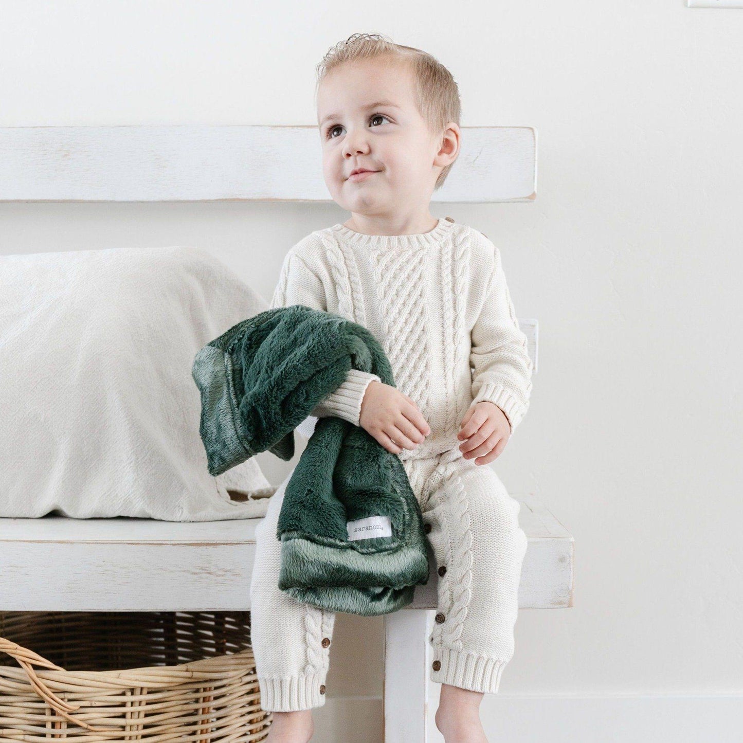 A little boy holds a Hunter Green Colored Lush Saranoni Blanket. The soft blanket is a small blanket and a baby blanket or toddler blanket.