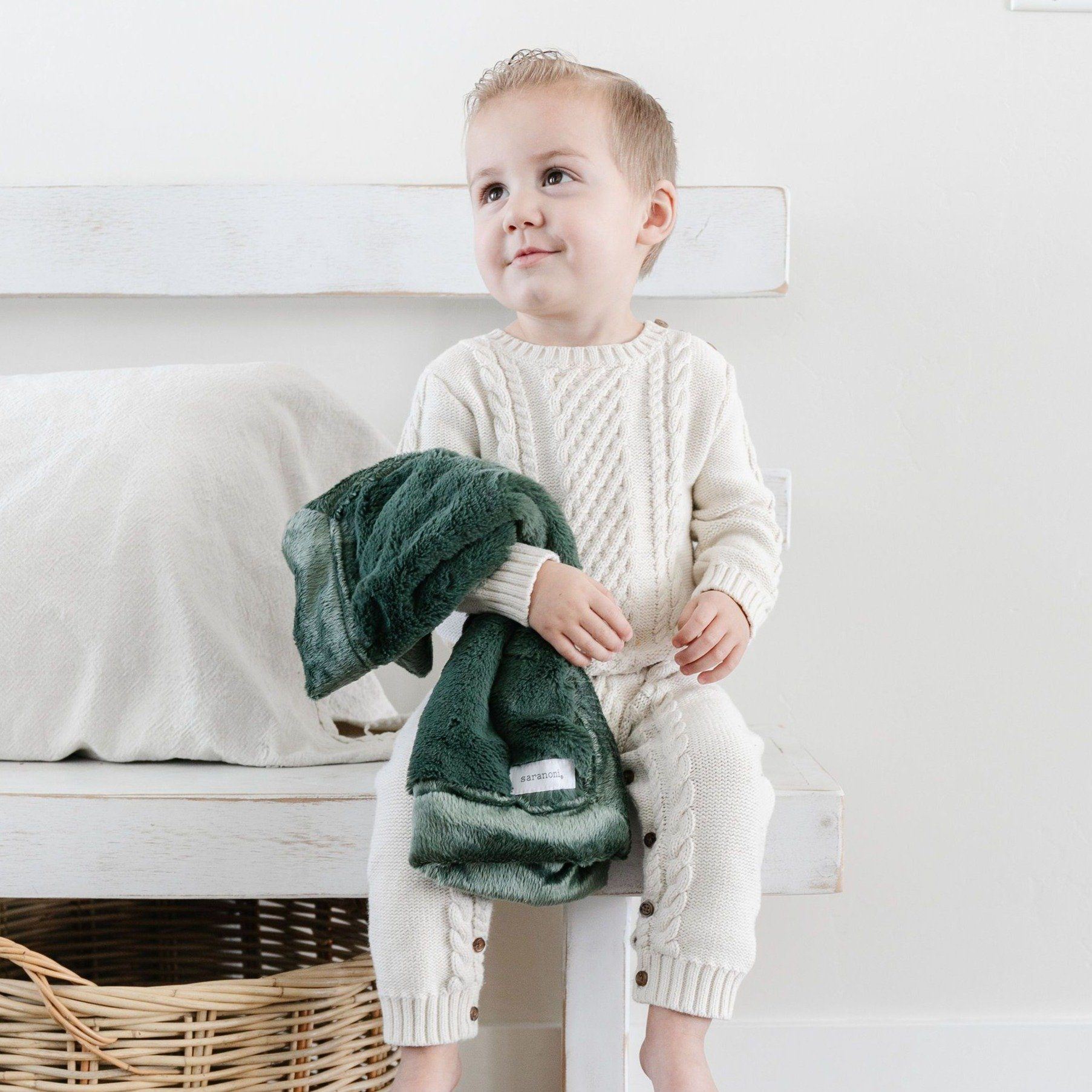 A little boy holds a Hunter Green Colored Lush Saranoni Blanket. The soft blanket is a small blanket and a baby blanket or toddler blanket.