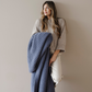 A woman is holding a Saranoni blanket that is a blue waffle knit blanket. This soft blanket is a luxury blanket and a Saranoni blanket. Use this blanket as a comfort gift, relaxation blanket, or home decor. 