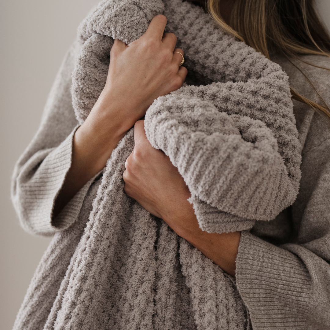 A light tan blanket that is a waffle knit blanket. This luxury blanket is a Saranoni blanket and is super cozy. It can be used for home decor, relaxing, gifting. 