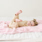 Little girl laying on super soft and stretchy, light pink BAMBONI RECEIVING BLANKETS - Saranoni