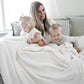Mom, little boy, and little girl all laughing and smiling, snuggled in their Ivory BAMBONI XL BLANKETS - Saranoni