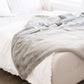 XL Grand Faux Fur blanket draped over a bed.