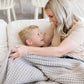 Mother and son enjoying time together on couch while wrapped in light gray waffle knit throw blanket.