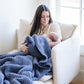 Mother snuggling up with baby, wrapped in blue waffle knit blanket.